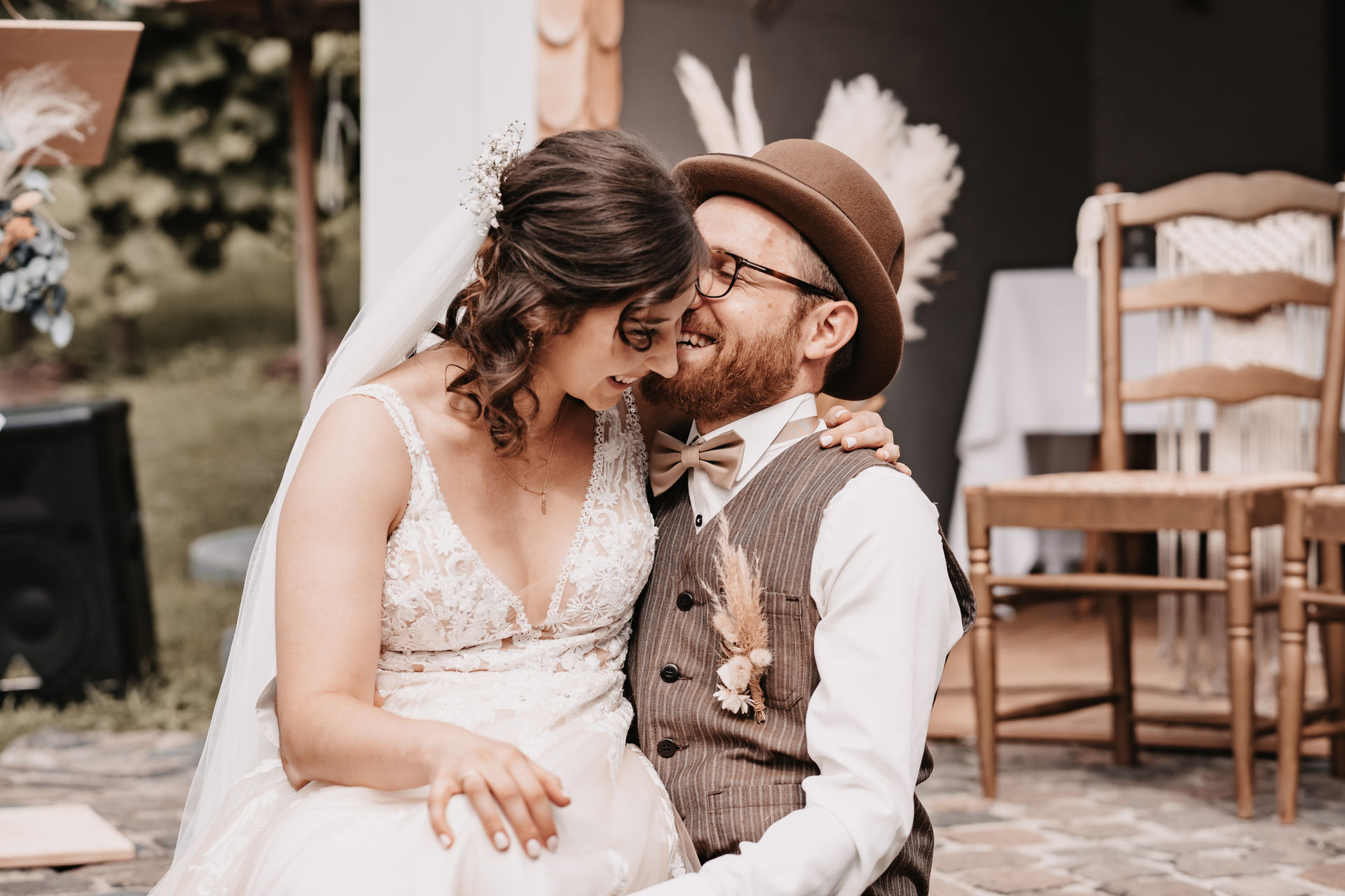 Braut und Bräutigam sitzen eng umschlungen auf dem Boden, lachen herzlich und drücken die Stirn aneinander – inniger Moment voller Freude bei einer freien Trauung, festgehalten in emotionaler Hochzeitsfotografie in Baden-Baden.